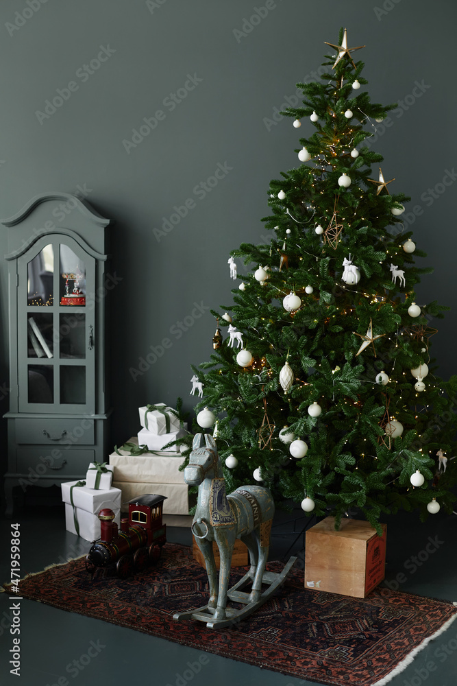 Decorated Christmas tree with Christmas gift boxes and other decorations in the dark cozy interior of the living room