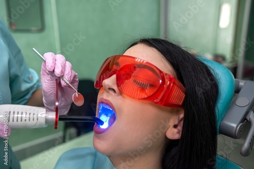 Dentist examining patient teeth with uv lamp close up