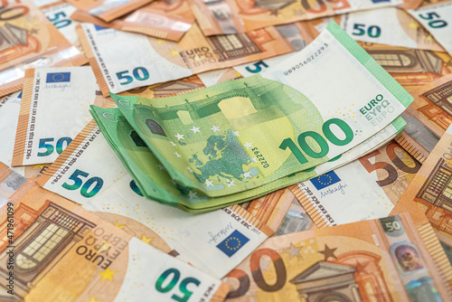  banknotes of 50 euros are laid out and on them are banknotes of 100 euros on the table