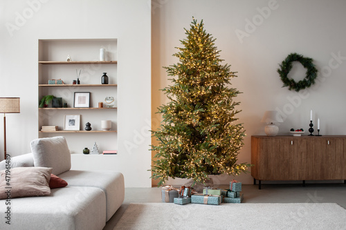 Stylish christmas living room interior with sofa, lamp, christmas tree and wreath, stars, gifts and decoration. Family time. Template. photo