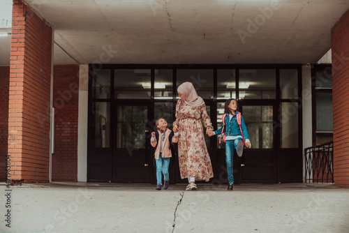 Hijab muslim mother walking her kids to school. Selective focus