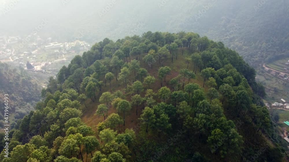 Flying over and around the edge of a mountain in Nepal to reveal the valley and a small town in the green terraced fields. Flying over and around the edge of a mountain in Nepal to reveal the valley and a small town in the green terraced fields.