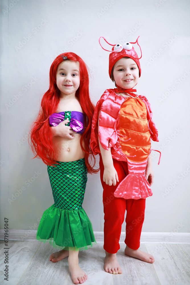 Children in smart carnival costumes on a plain background. Costume of sea fairy creatures. Mermaid and crab.