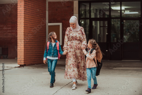 Hijab muslim mother walking her kids to school. Selective focus