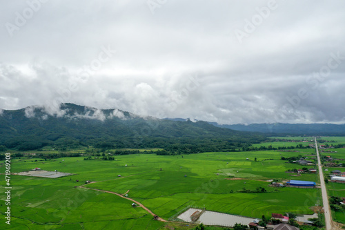 Scenic view of  green field against mountain in cloudy sky