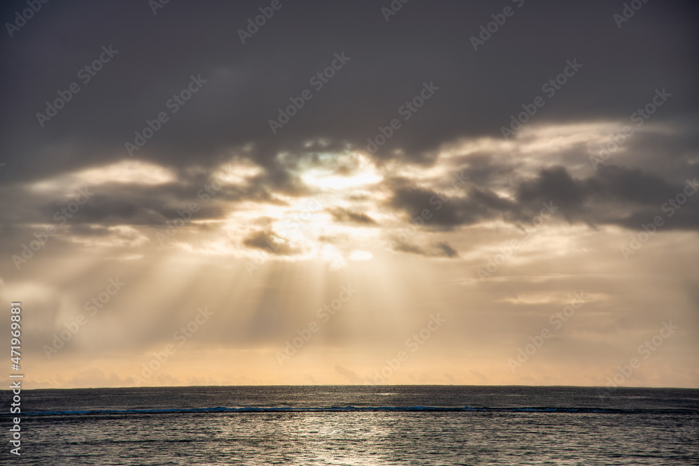 Sun rays through the cloudy sky at dusk.