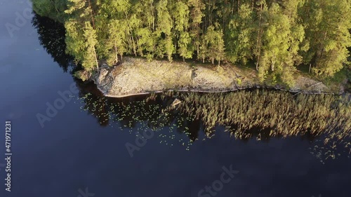 Aerial drone shot of a cliff on a shoreline by sunset. Slowly tilting down and forwarding. photo