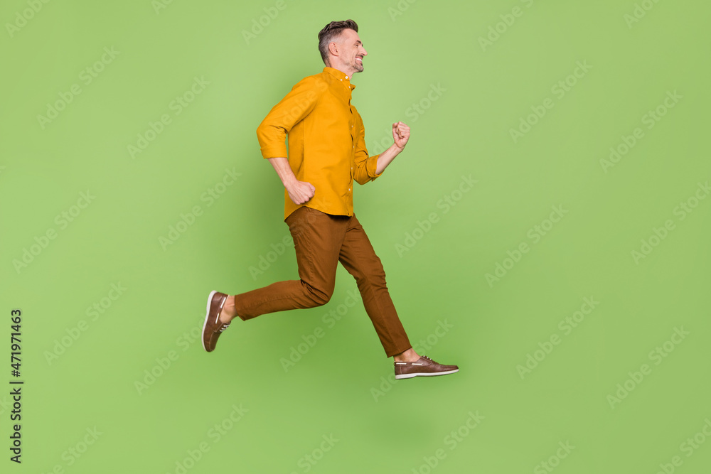 Full body profile side photo of mature man run energetic discount isolated over green color background Full body profile side photo of mature man run energetic discount isolated over green color background