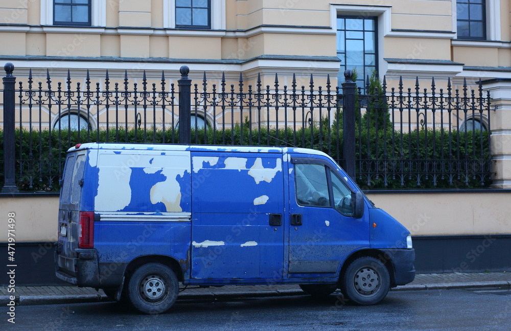 A shabby blue minibus is parked at the fences of the mansion, ulitsa Malaya Sadovaya, St. Petersburg, Russia, November 2021