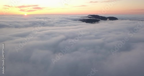 Valderøya, an island in western Norway is covered in a unique, fast moving, low level cloud blanket at sunset in winter time. Cinematic forward flying hyper lapse towards the setting sun. photo