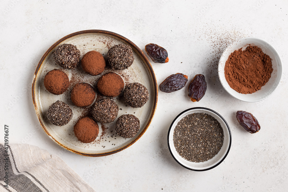 healthy energy balls with dates, chia seeds and cacao on ceramic plate. Vegan alternative food. White background. flat lay healthy energy balls with dates, chia seeds and cacao on ceramic plate. Vegan alternative food. White background. flat lay