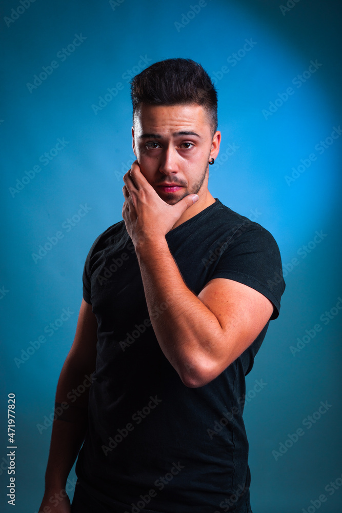 Young caucasian man portrait in a photography studio with a blue background.