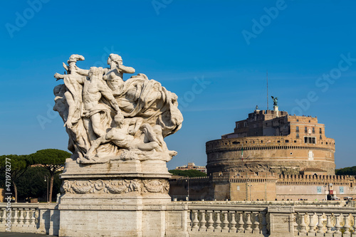 Statue on Vittorio Emanuele II bridge on Tiber river with the Castel Sant'Angelo (Castle of the Holy Angel) in background, Rome, Italy © Baharlou