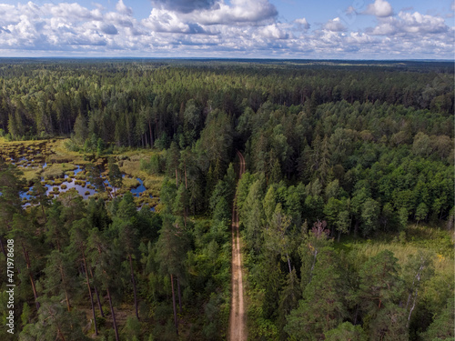 Areal drone view of small road through forest.