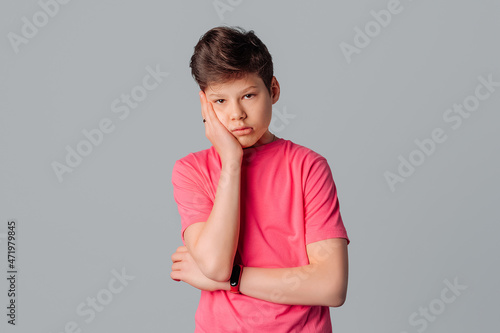 Portrait of handsome teenager boy in pink t-shirt over isolated gray background thinking looking tired and bored with study problems