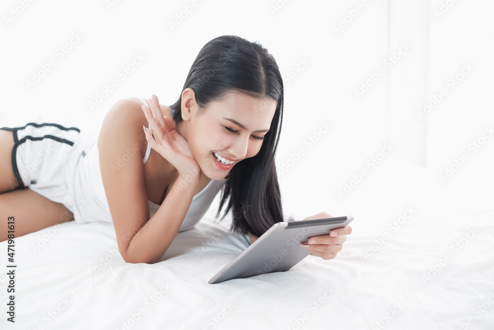 Asia woman lying on the bed in morning with tablet Asia woman lying on the bed in morning with tablet