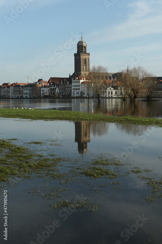 A view on the old buildings and the Great Church in the city of Deventer, the Netherlands, with reflection in a flooded meadow 