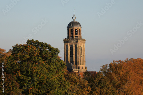 The tower of the Great Church in the city of Deventer, the Netherlands, can be seen above the colorful trees in autumn photo