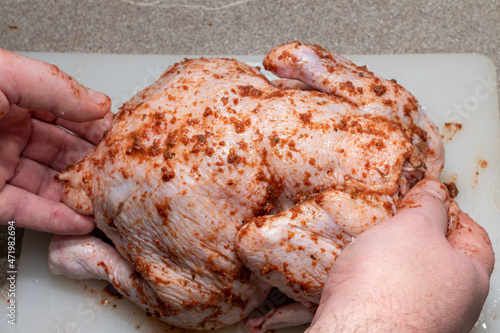 Male hands covering raw whole chicken with sauce for cooking, close-up. Cooking a meat dish for a holiday