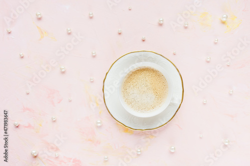 Cup of espresso on pastel pink with pearls abstract woman background. Drinking coffee, coffee break concept. Top view, flat lay, copy space
