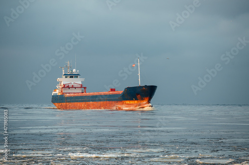 A small ship enters the port. Bulk carrier.