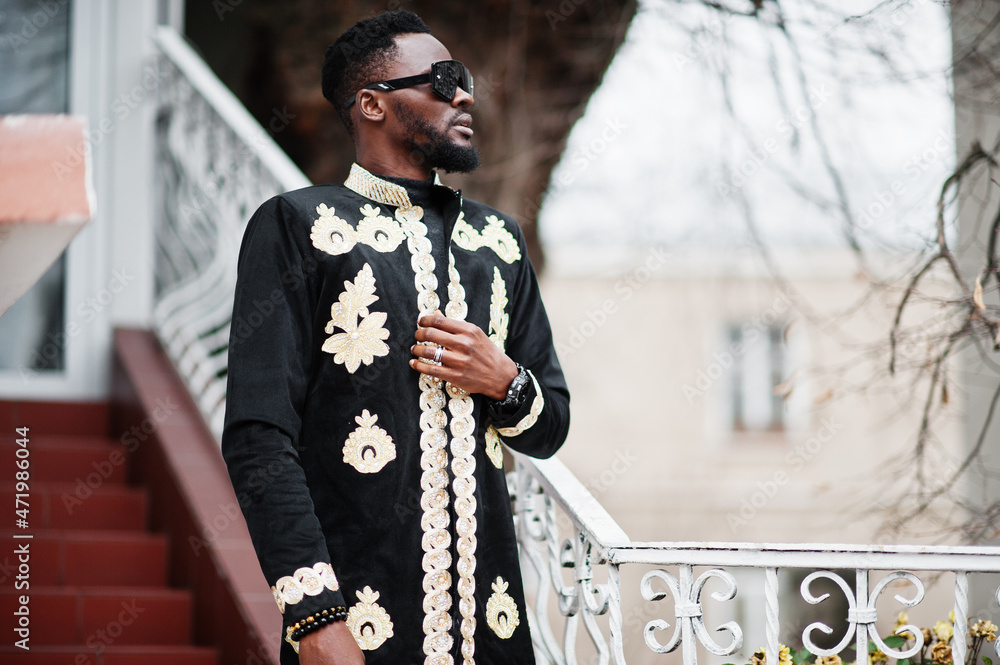 Fototapeta premium Mega stylish african man in traditional jacket pose. Fashionable black guy in sunglasses.