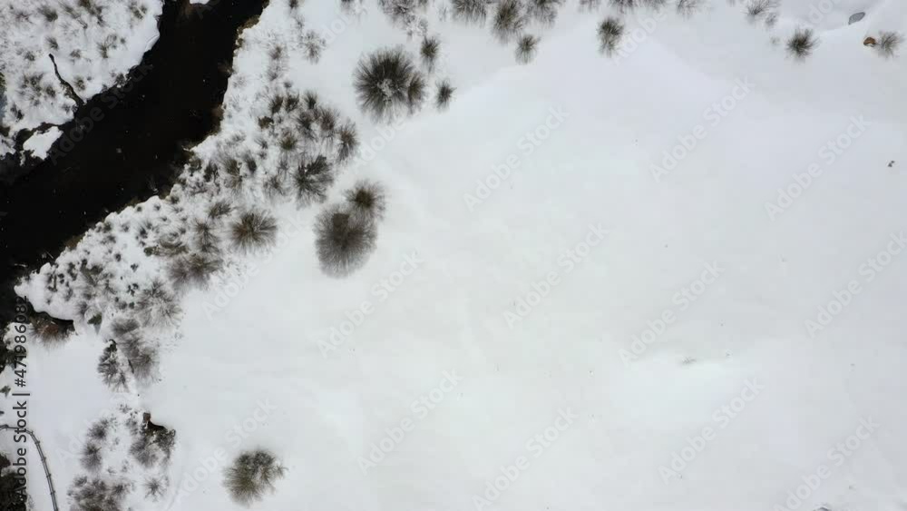 Beautiful river surrounded by snowy landscape in winter season. Snowfall. Aerial top down view Beautiful river surrounded by snowy landscape in winter season. Snowfall. Aerial top down view