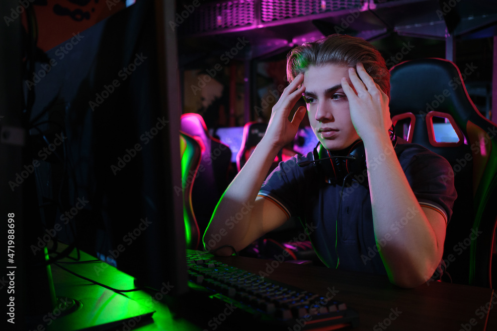 Professional young caucasian gamer playing online on his PC. He upset because of losing the game Professional young caucasian gamer playing online on his PC. He upset because of losing the game