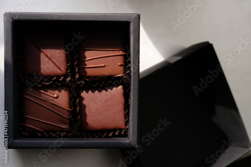 Chocolate gift set in a black box. Four pralines in brown paper cups. Craft chocolate in Ukraine. Natural sunlight.