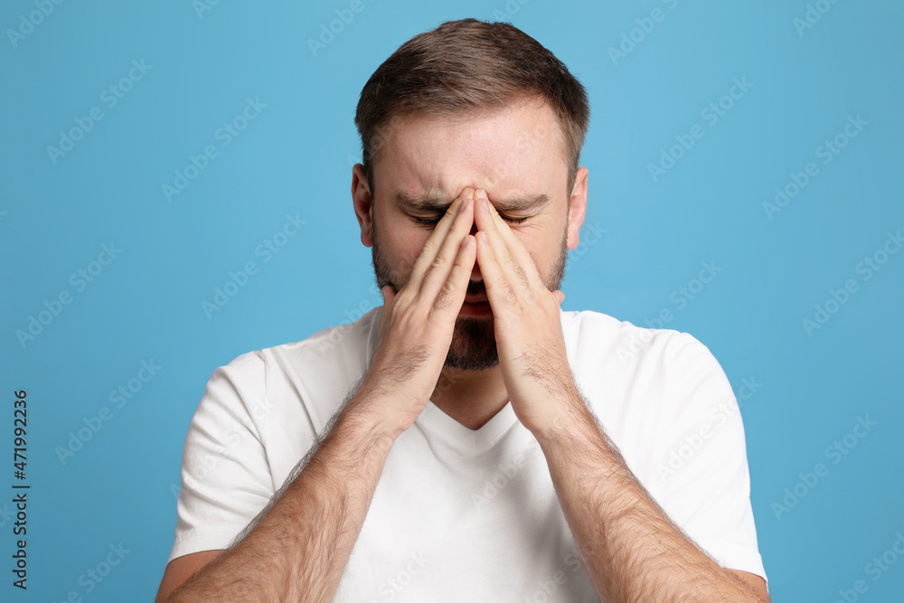 Young man suffering from headache on light blue background Young man suffering from headache on light blue background