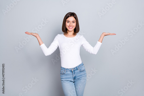 Принти на полотні Photo of charming cute young woman wear white outfit comparing arms empty space