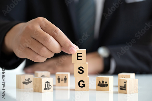 Businessman holding wooden cube with text "ESG" surrounding with ESG icon on white background.ESG of environmental concept, account the environment, society and corporate governance