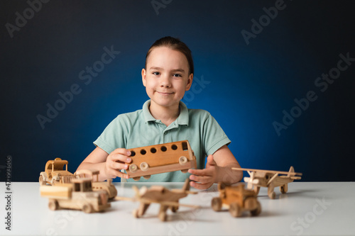 School boy playing, hands holding with wooden toys on white table, while staying at home on blue enlighted background photo