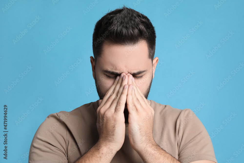Young man suffering from headache on light blue background Young man suffering from headache on light blue background