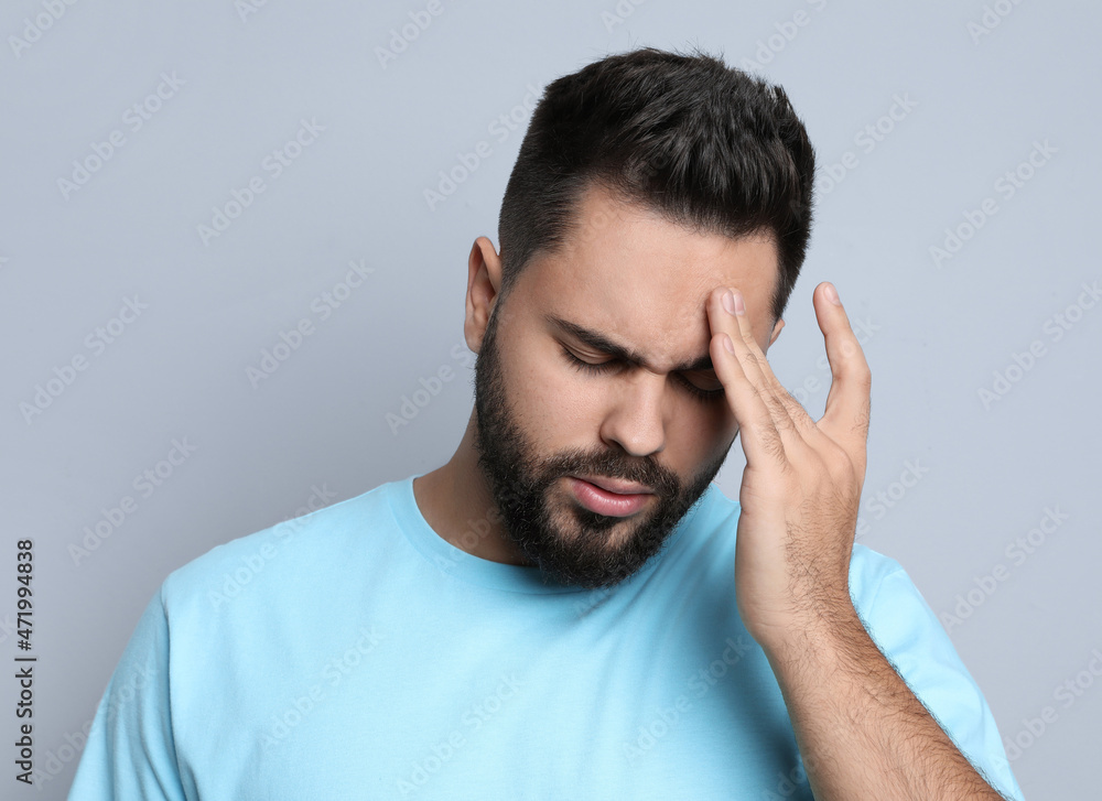 Young man suffering from headache on light grey background Young man suffering from headache on light grey background