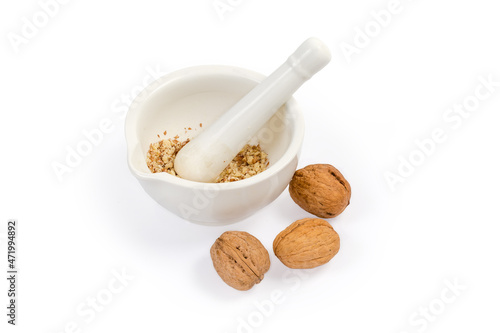 Crushed walnuts in kitchen mortar with pestle and whole nuts