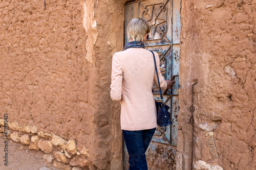 Fototapeta Naklejka Na Ścianę i Meble -  A Western female tourist standing at the old metal door in Ushaiqer Heritage Village, Saudi Arabia. Back view.