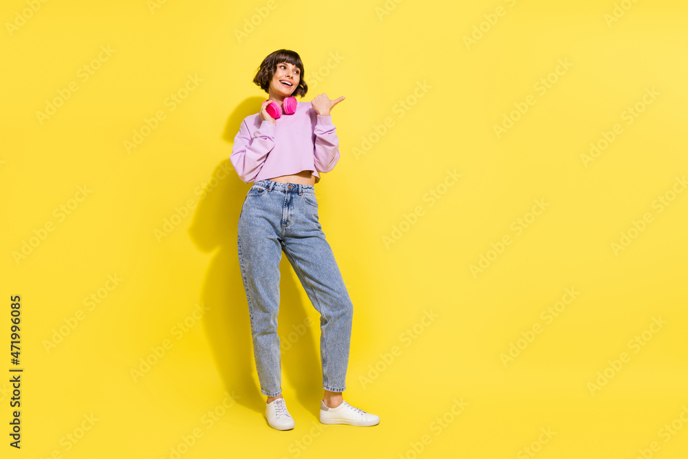 Full length body size view of attractive cheerful girl listening hit showing copy space isolated over bright yellow color background Full length body size view of attractive cheerful girl listening hit showing copy space isolated over bright yellow color background