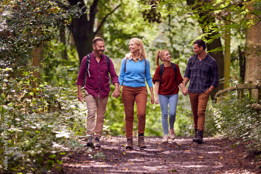 Mature And Mid Adult Couples In Countryside Hiking Along Path Through Forest Together Mature And Mid Adult Couples In Countryside Hiking Along Path Through Forest Together
