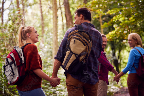 Rear View Of Mature And Mid Adult Couples In Countryside Hiking Along Path Through Forest Together © Monkey Business