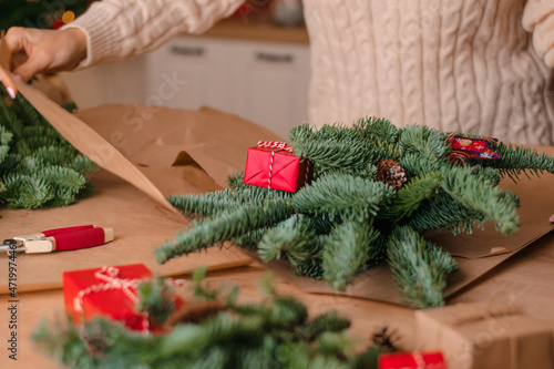 The process of making a winter bouquet of fir branches at home  packaging in kraft paper close-up of the woman s hands.New Year  Christmas and eco-friendly concept.Selective focus.