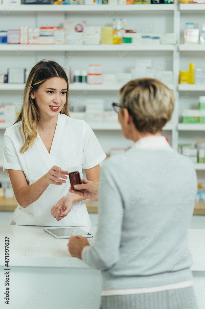 Female pharmacist selling medications at drugstore to a senior woman customer