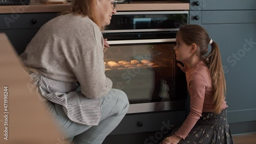 Grandmother and granddaughter waiting for homemade cookies next to the oven. Shot with RED helium camera in 8K   