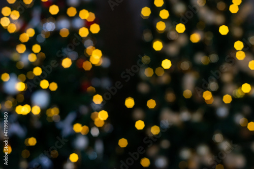 Blurred multicolored lights of a garland and branches of a Christmas tree in the foreground.Christmas and New Year background.Selective focus copy space.