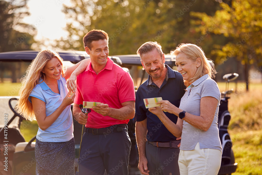 Mature And Mid Adult Couples Standing By Golf Buggy Checking Score Cards Together Mature And Mid Adult Couples Standing By Golf Buggy Checking Score Cards Together