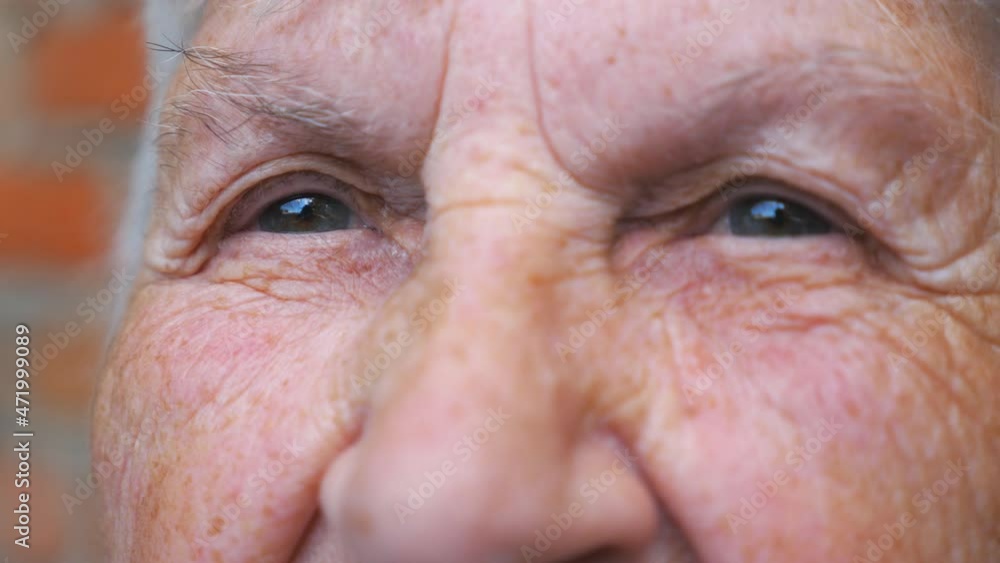 Portrait of elderly woman watching pensive into camera. Close up of wrinkled female face. Grandmother with calmly facial expression. Detail view Slow motion Portrait of elderly woman watching pensive into camera. Close up of wrinkled female face. Grandmother with calmly facial expression. Detail view Slow motion