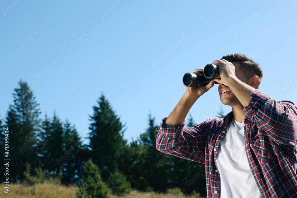 Man looking through binoculars outdoors on sunny day Man looking through binoculars outdoors on sunny day