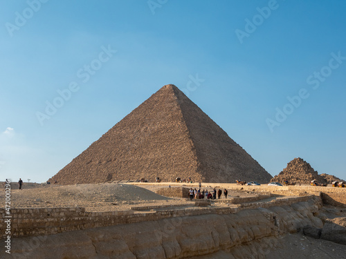 Giza  Cairo  Egypt - September 30  2021  View of the Egyptian pyramid on the Giza plateau against the background of the blue sky. Tourists go sightseeing and take photos.