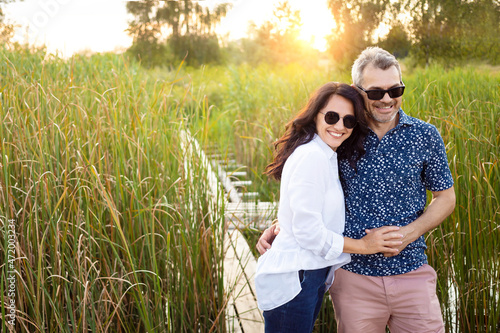 Romantic and elderly healthy lifestyle concept. Senior active caucasian couple holding hands looking happy in park in midday autumn sunlight, happy anniversary