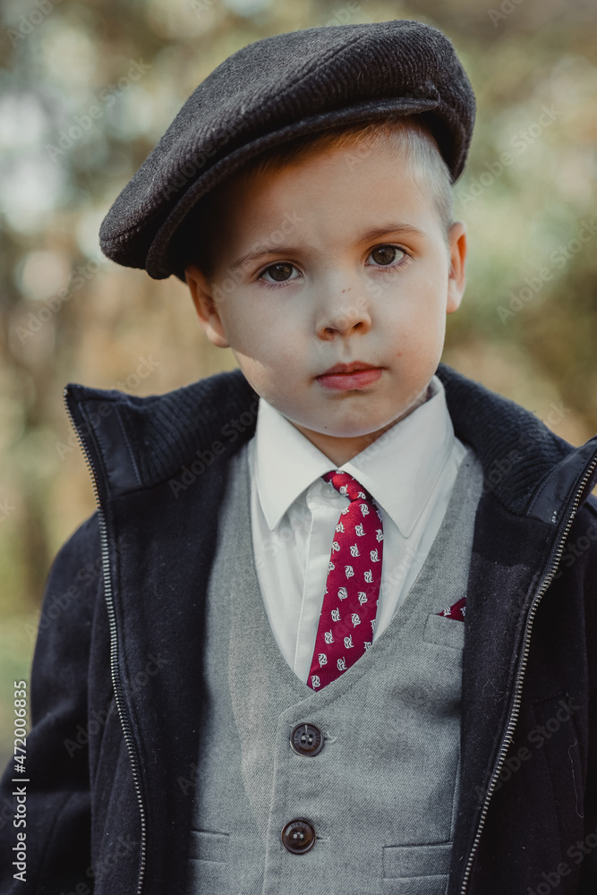 child boy in a coat and with a suitcase in a big cap child boy in a coat and with a suitcase in a big cap